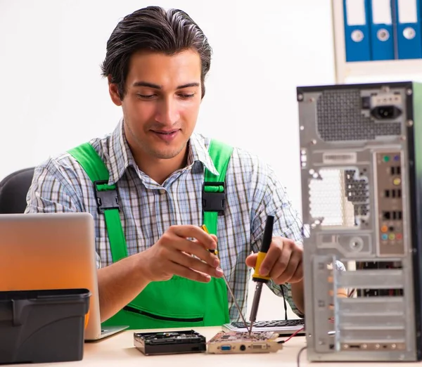 Молодой инженер ремонтирует сломанный компьютер в офисе — стоковое фото