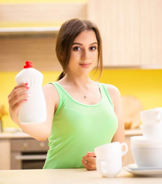 Jovem mulher de limpeza e lavagem de pratos na cozinha — Fotografia de Stock