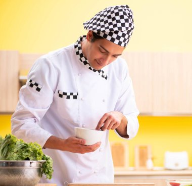 Genç profesyonel aşçı evde salata hazırlıyor.