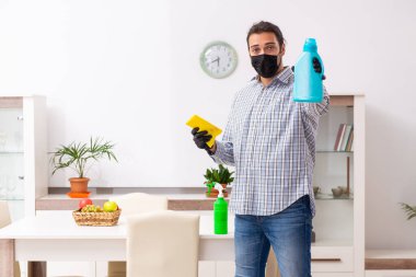 Genç erkek müteahhit Coronavirus konseptiyle evi temizliyor.