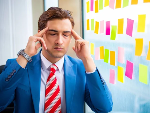 Joven empleado guapo con muchas prioridades contradictorias — Foto de Stock