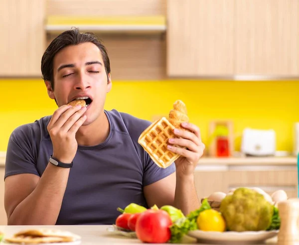 Homem tendo escolha difícil entre alimentos saudáveis e não saudáveis — Fotografia de Stock