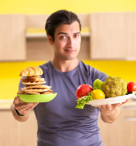 Sağlıklı ve sağlıksız yemek arasında zor bir seçim yapan bir adam. — Stok fotoğraf