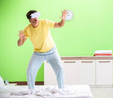 Yatak odasında sanal gözlüklü genç adam.