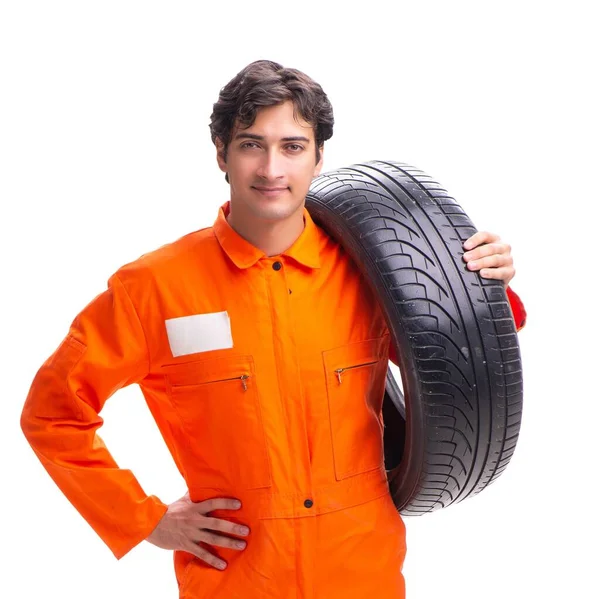 Junger Werkstattarbeiter mit Reifen auf weißem Untergrund — Stockfoto