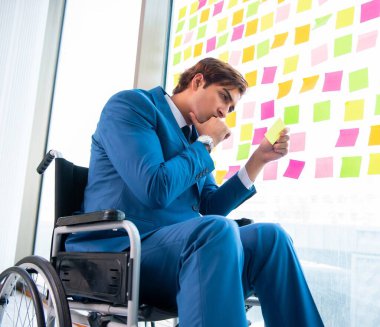 Birçok çelişkili önceliği olan tekerlekli sandalyedeki genç yakışıklı adam.