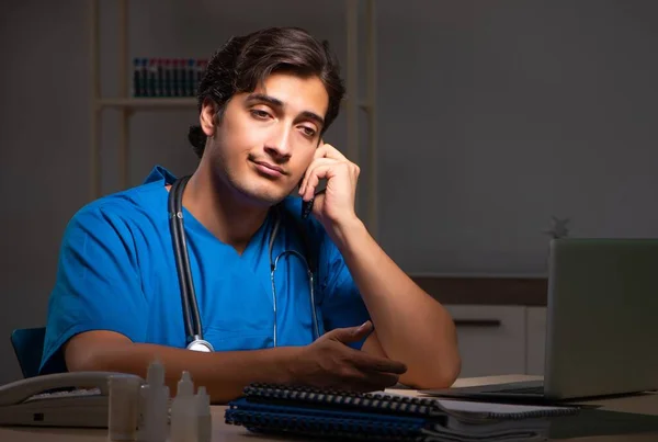 Fiatal jóképű orvos éjszakai műszakban dolgozik a kórházban. — Stock Fotó