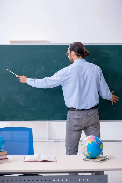 Jonge mannelijke aardrijkskunde leraar voor schoolbord — Stockfoto