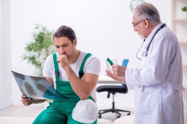 Genç erkek müteahhit yaşlı doktoru ziyaret ediyor.