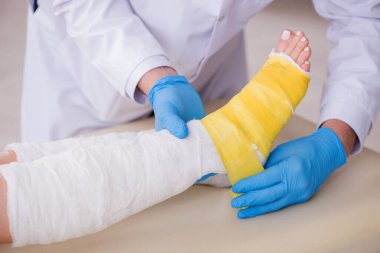 Genç bacak yaralı kadın yaşlı doktor travmatoloğu ziyaret ediyor.