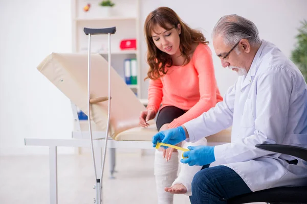 Genç bacak yaralı kadın yaşlı doktor travmatoloğu ziyaret ediyor. — Stok fotoğraf