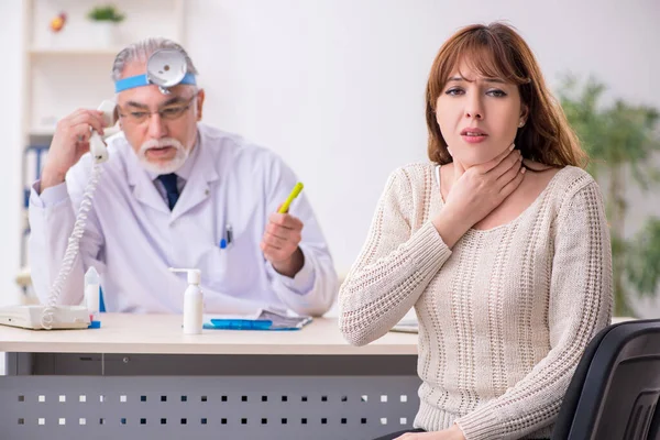 Jovem mulher visitando velho médico otorrinolaringologista masculino — Fotografia de Stock