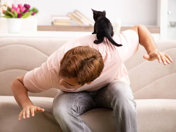 Молодой человек играет с котенком дома — стоковое фото