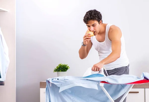 Hombre joven planchando en el dormitorio — Foto de Stock