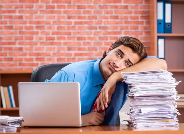 Young employee with excessive work sitting at the office — Stock Photo, Image