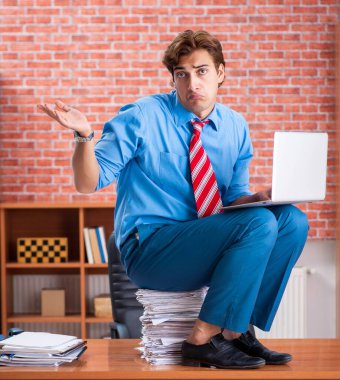 Ofiste aşırı işi olan genç bir çalışan oturuyor.