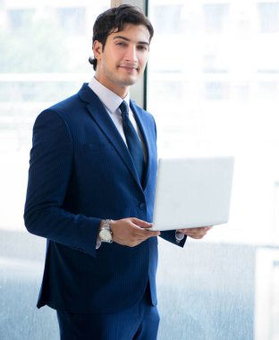 Genç yakışıklı işadamı pencerede duruyor.