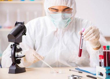 Genç yakışıklı laboratuvar asistanı hastanede kan örnekleri test ediyor.