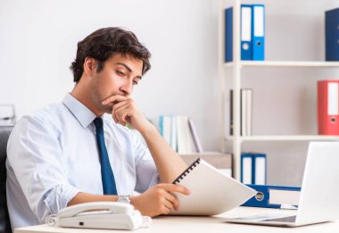 Genç yakışıklı işadamı ofiste çalışıyor.