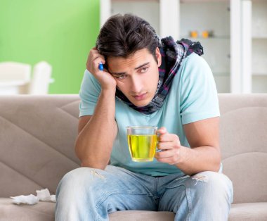 Evde hastalıktan muzdarip genç yakışıklı bir adam.