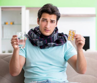 Evde hastalıktan muzdarip genç yakışıklı bir adam.