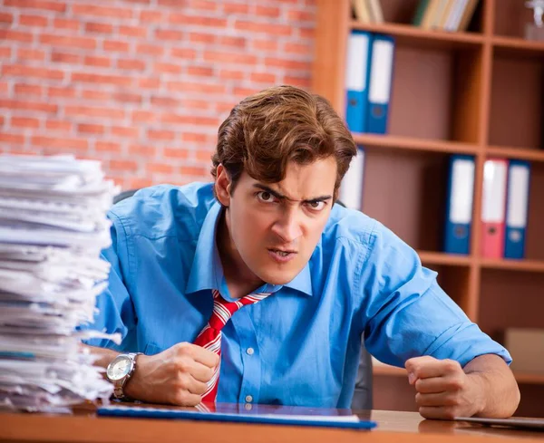 Ung anställd med överdrivet arbete sittande på kontoret — Stockfoto