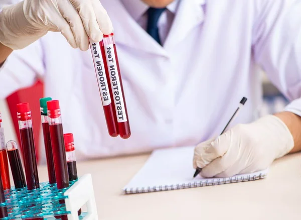 Asistente de laboratorio joven guapo analizando muestras de sangre en el hospital — Foto de Stock