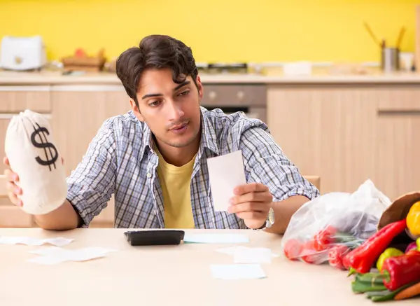 Junger Mann berechnet Ausgaben für Gemüse in der Küche — Stockfoto