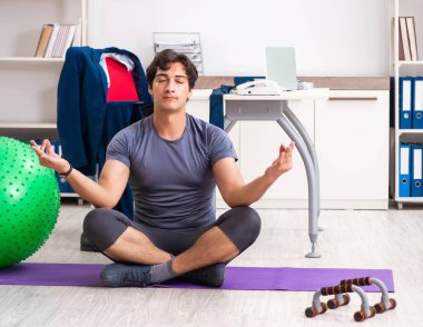 Ofiste egzersiz yapan genç bir erkek.