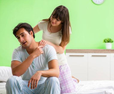 Yatak odasında kocasına masaj yapan bir kadın.