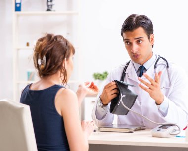 Genç doktor, kadınların tansiyonunu ölçüyor.