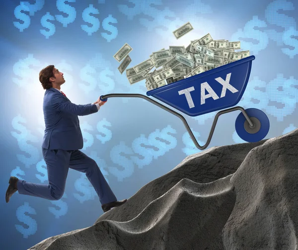 Businessman pushing tax wheelbarrow uphill — Stock Photo, Image