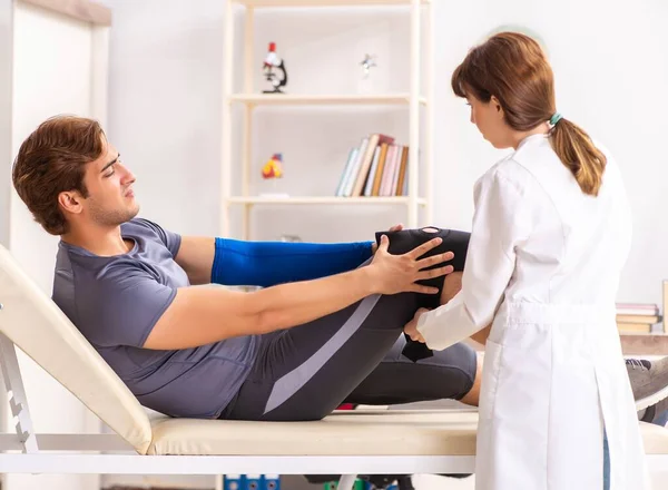 Jovem paciente do sexo masculino visitando médico traumatologista feminino — Fotografia de Stock