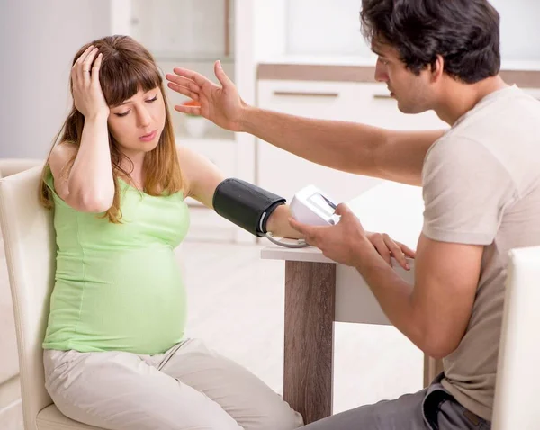 Husband checking pregnant wifes blood pressure