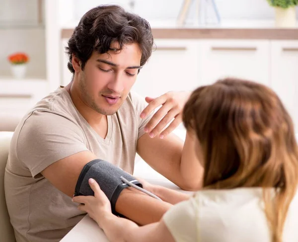 Wife checking husbands blood pressure — Stock Photo, Image