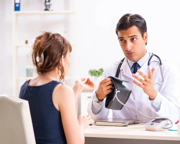 Médico joven revisando la presión arterial de las mujeres — Foto de Stock