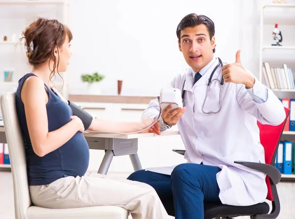 Молодой врач проверяет кровяное давление беременных женщин — стоковое фото