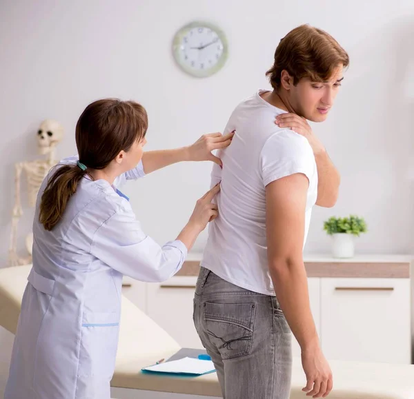 Paciente masculino que visita a una joven doctora quiropráctica — Foto de Stock