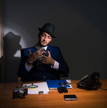 Dedektif karanlık odada klasik bir konseptle oturuyor.