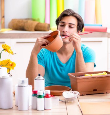 Sınıfta çömlek dekorasyonu yapan genç bir adam.