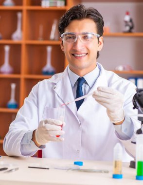 Genç yakışıklı biyokimyacı laboratuvarda çalışıyor.