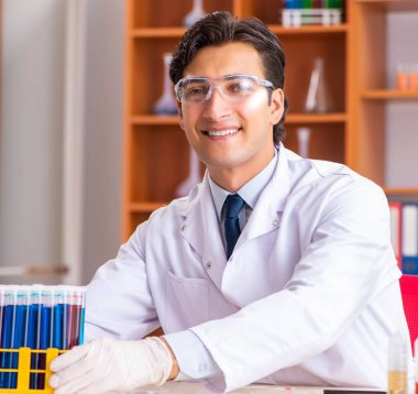 Genç yakışıklı biyokimyacı laboratuvarda çalışıyor.