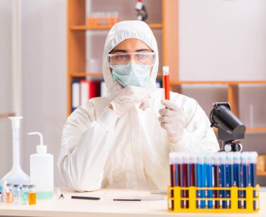 Laboratuvarda çalışan koruyucu elbise giyen genç bir biyokimyacı.