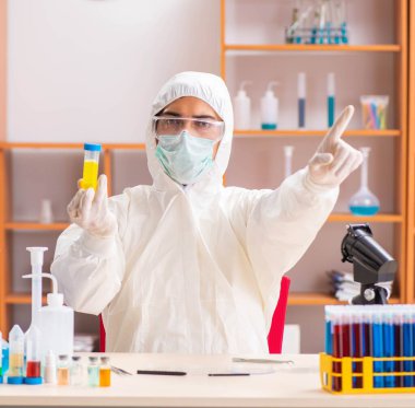 Laboratuvarda çalışan koruyucu elbise giyen genç bir biyokimyacı.