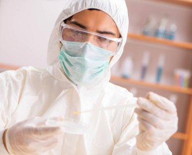 Laboratuvarda çalışan koruyucu elbise giyen genç bir biyokimyacı.