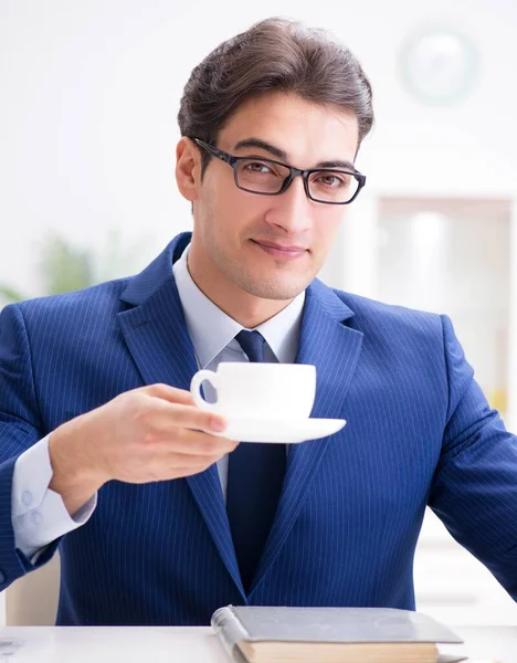 Junger schöner Geschäftsmann trinkt Kaffee im Büro — Stockfoto