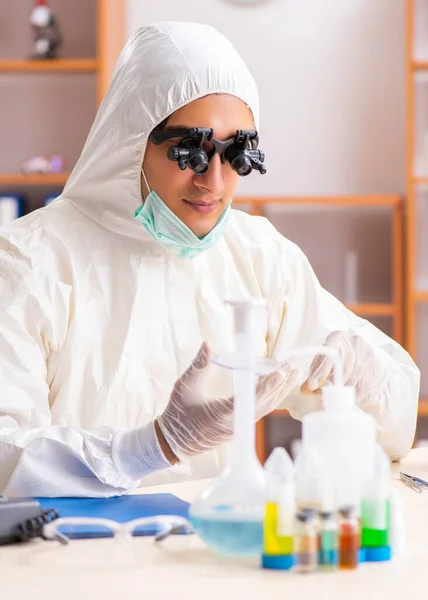 Молодой биохимик в защитном костюме работает в лаборатории — стоковое фото