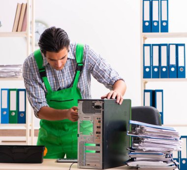 Ofiste bozuk bilgisayarı tamir eden genç bir mühendis.