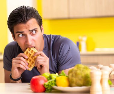 Sağlıklı ve sağlıksız yemek arasında zor bir seçim yapan bir adam.