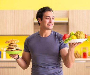 Sağlıklı ve sağlıksız yemek arasında zor bir seçim yapan bir adam.